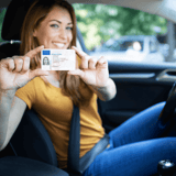 Person holding a driving license inside a car.