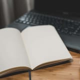 Laptop, notebook, coffee for writing and editing text on digital device, workspace, detail, still life, cozy atmosphere, productivity.