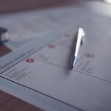 Close-up of a word count sheet with pen and documents, emphasizing the importance of word counting for content writing and editing.