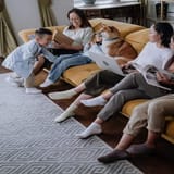 Alt text: Family relaxing on sofa with dog, reading and using devices in cozy living room.