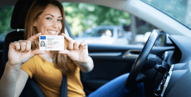 Person holding a driving license inside a car.