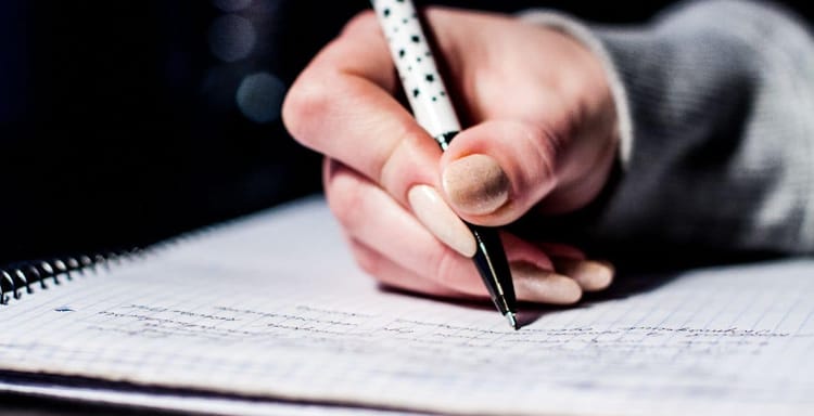 Hand writing on a notebook with pen for word count.