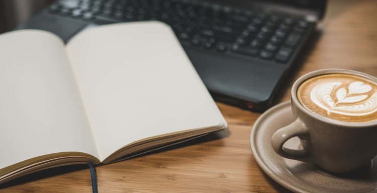 Laptop, notebook, coffee for writing and editing text on digital device, workspace, detail, still life, cozy atmosphere, productivity.