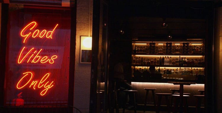 Neon sign "Good Vibes Only" at bar.