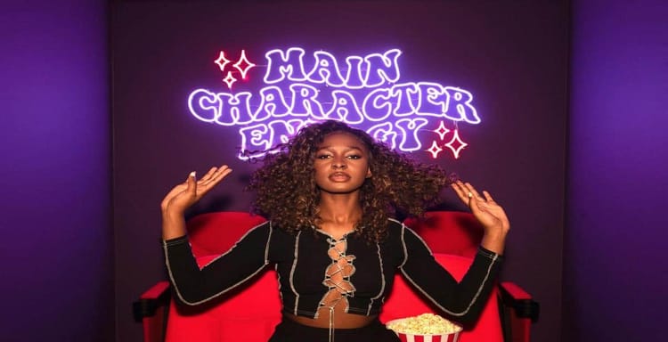 Neon sign reading "Main Character Energy" behind confident woman.