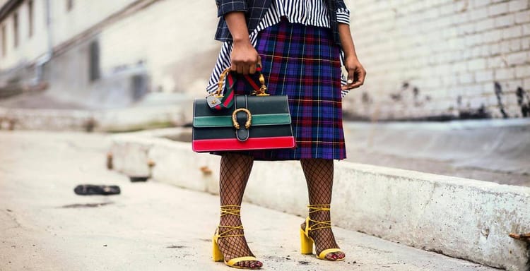 Stylish woman with handbag, fashionable outfit, yellow heels on city street.