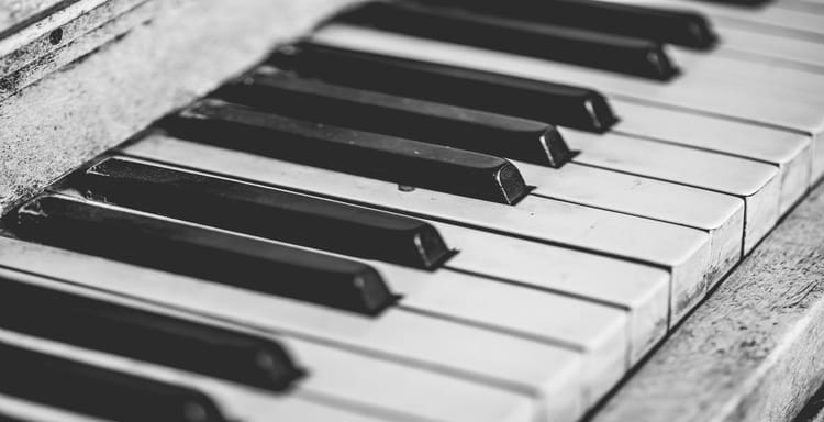 Close-up black and white piano keyboard with worn keys.