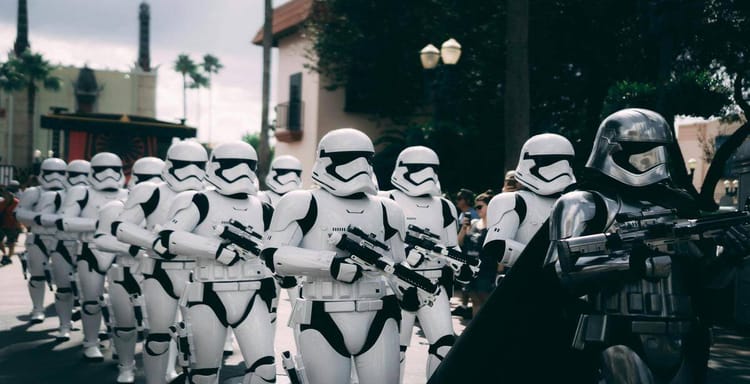 Stormtroopers in white armor holding blaster rifles at a parade or event.