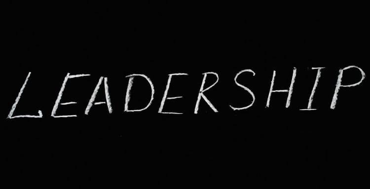 Alt text: Handwritten word "Leadership" on black background, emphasizing leadership skills and development.