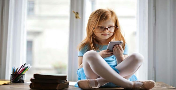 Child using phone for writing and editing texts at home.