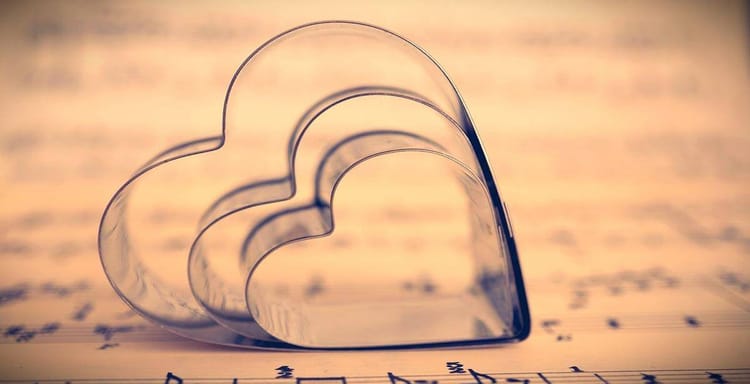 Love-themed cookie cutters placed on sheet music for baking and music lovers.