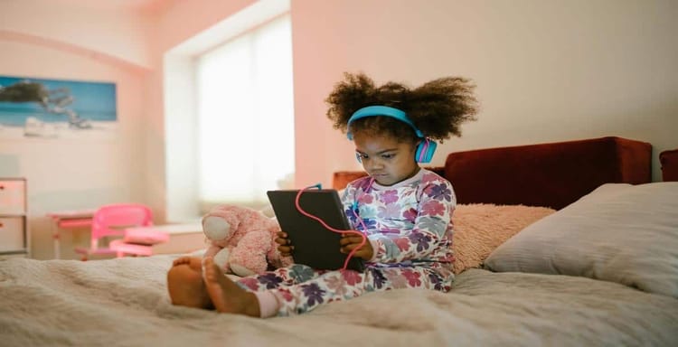 Child using tablet with headphones for writing and reading.