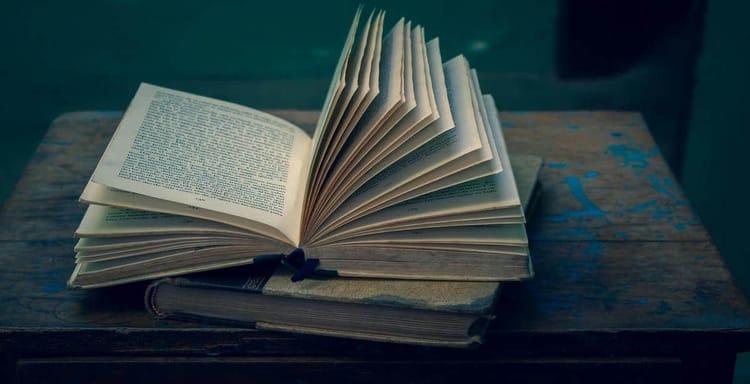 Open book with text on pages, on a rustic wooden table. Focus on writing, reading, text analysis.