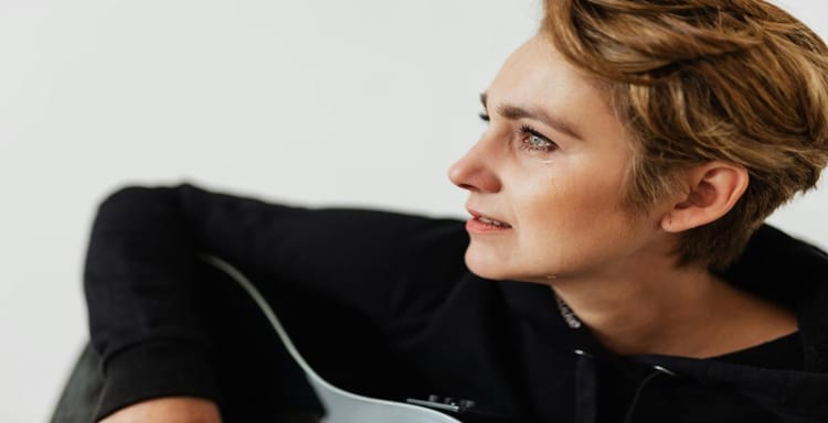 Close-up of a young woman with short hair reading and using a guitar, emphasizing writing and word counting tools.