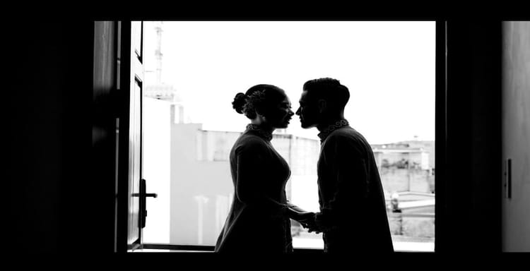 Romantic couple silhouette holding hands by window.