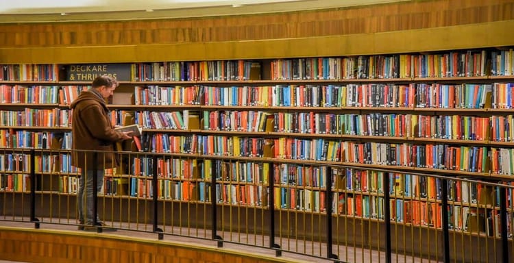 Alt text: Man reading book in a library with colorful shelves of books, emphasizing reading and word counting.