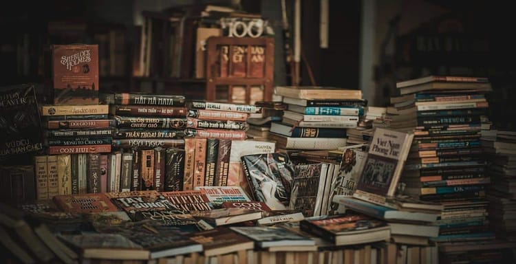 Books and reading materials on a cluttered table for writing and word counting.