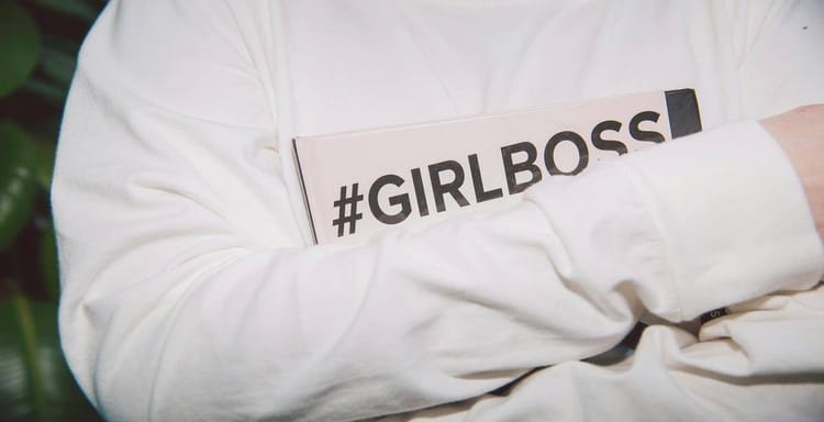 Girl boss holding a book with "#GIRLBOSS" hashtag, symbolizing women empowerment and leadership.