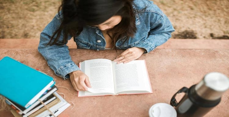 Mobile woman reading a book at a desk with a word counter app open, showcasing productivity and online writing tools.