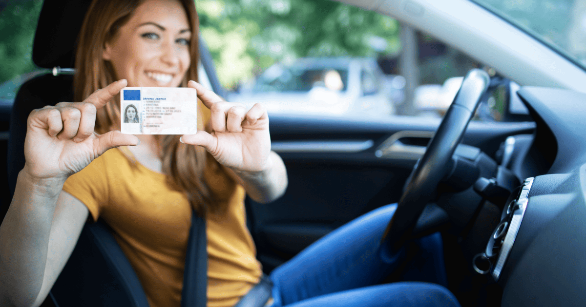 Person holding a driving license inside a car.
