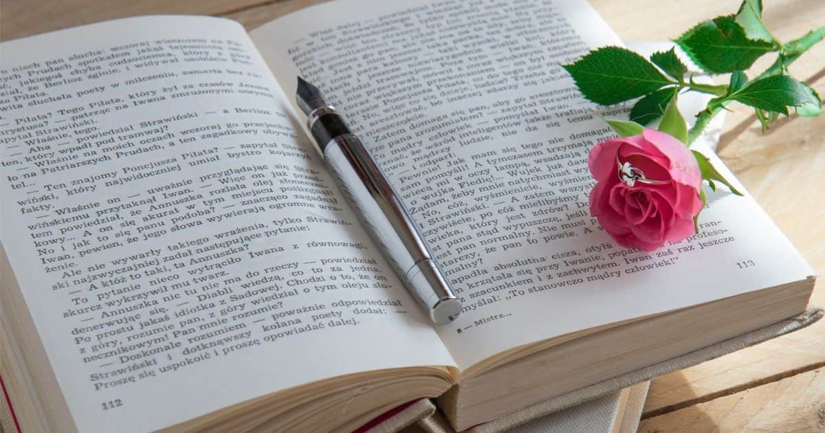 SEO-friendly alt text: Open book with a pen and pink rose, suitable for words count and writing tools.