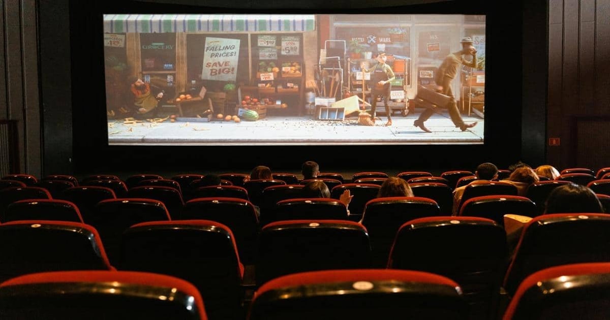People watching an animated film in a movie theater with red seats.