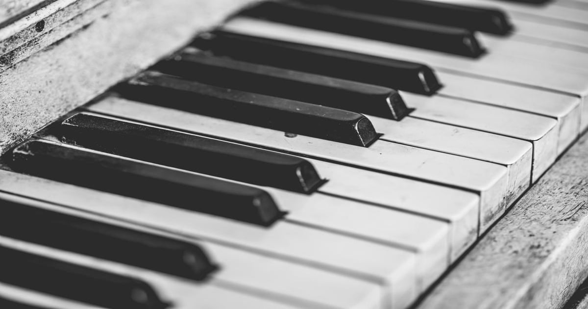 Close-up black and white piano keyboard with worn keys.