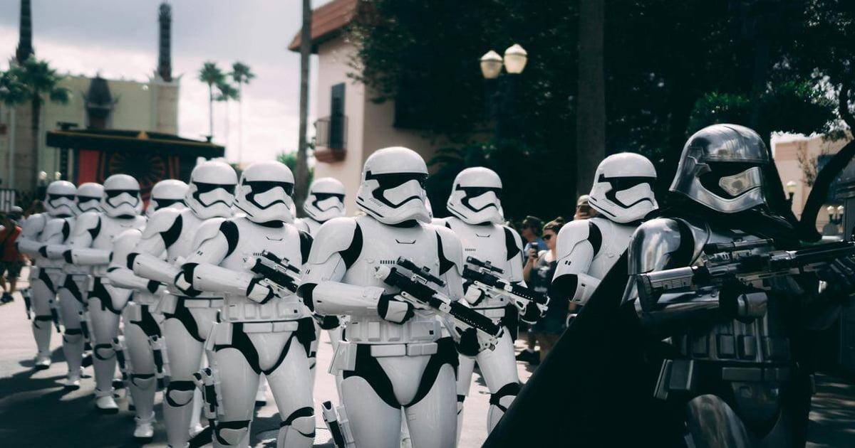 Stormtroopers in white armor holding blaster rifles at a parade or event.