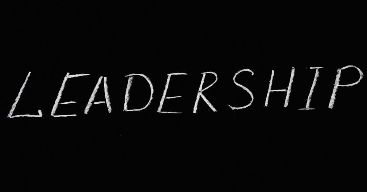 Alt text: Handwritten word "Leadership" on black background, emphasizing leadership skills and development.