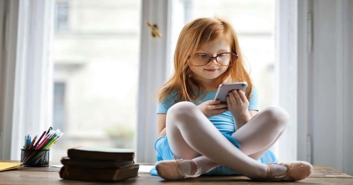 Child using phone for writing and editing texts at home.