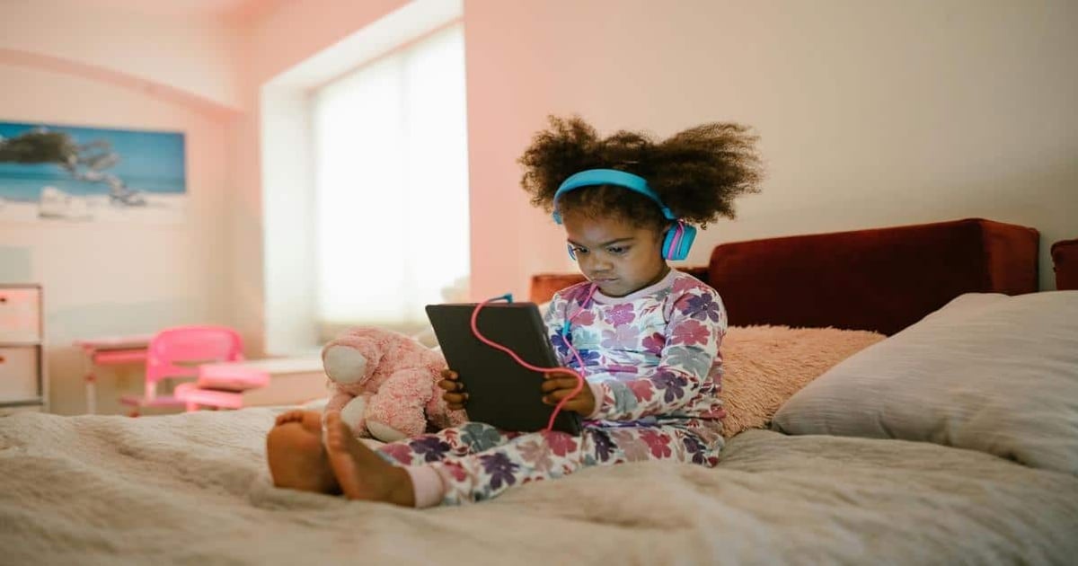Child using tablet with headphones for writing and reading.