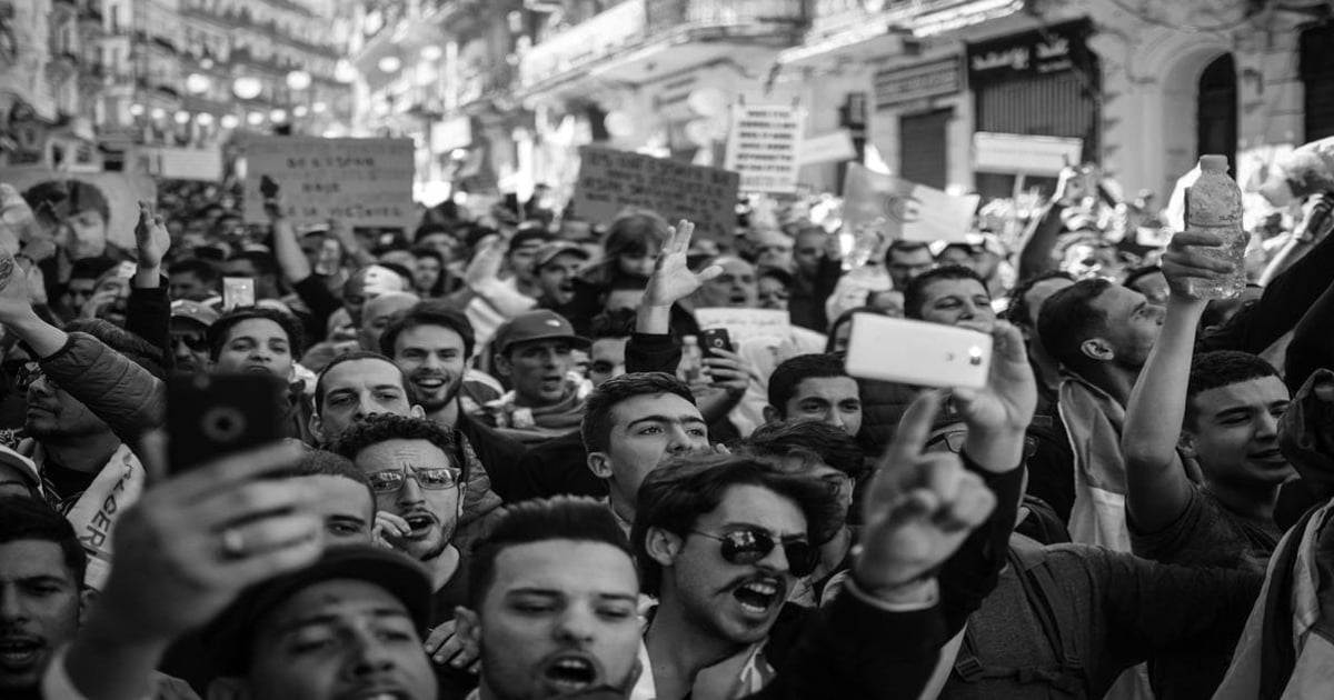 Large crowd of people protesting during a demonstration, holding signs and raising their hands.