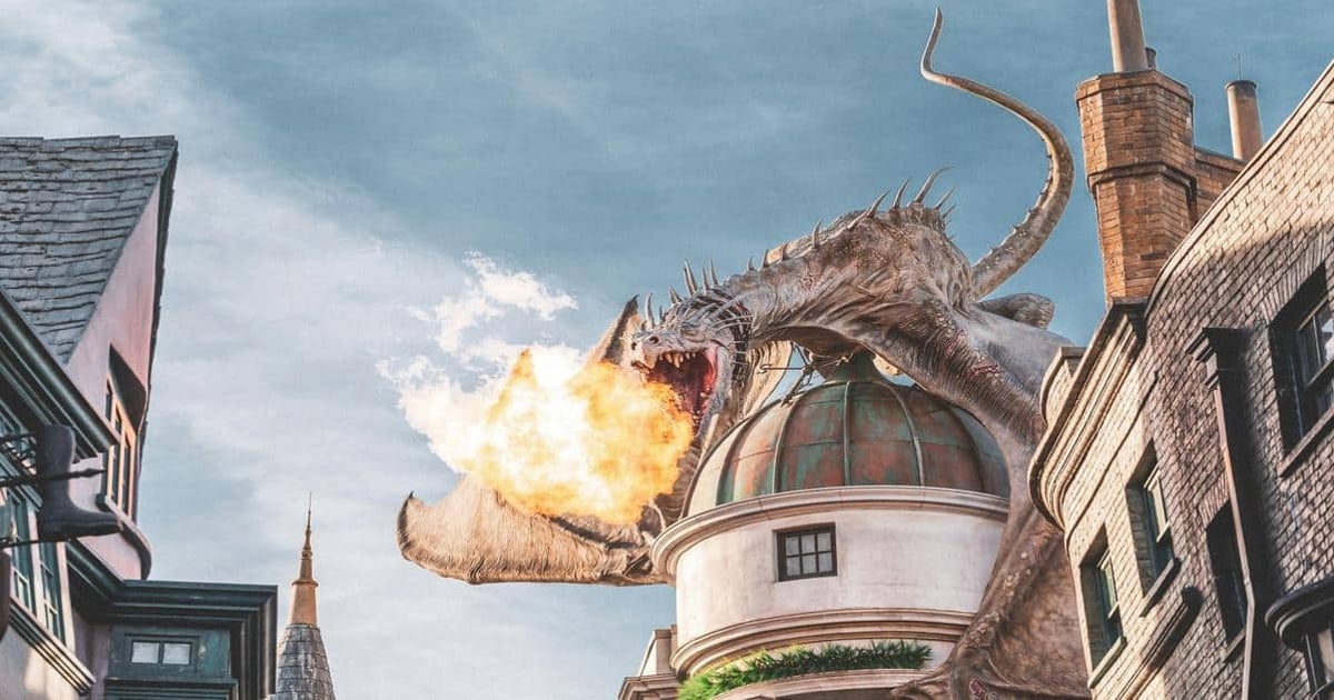 A giant dragon breathes fire atop a building in a cityscape scene.