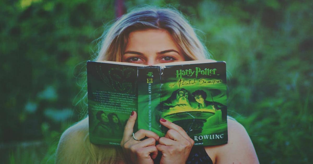Alt text: Woman reading Harry Potter book outdoors, emphasizing reading and writing tools.