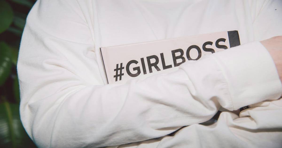 Girl boss holding a book with "#GIRLBOSS" hashtag, symbolizing women empowerment and leadership.