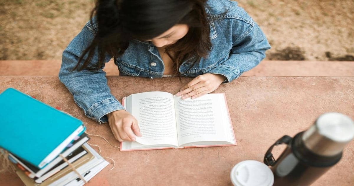 Mobile woman reading a book at a desk with a word counter app open, showcasing productivity and online writing tools.